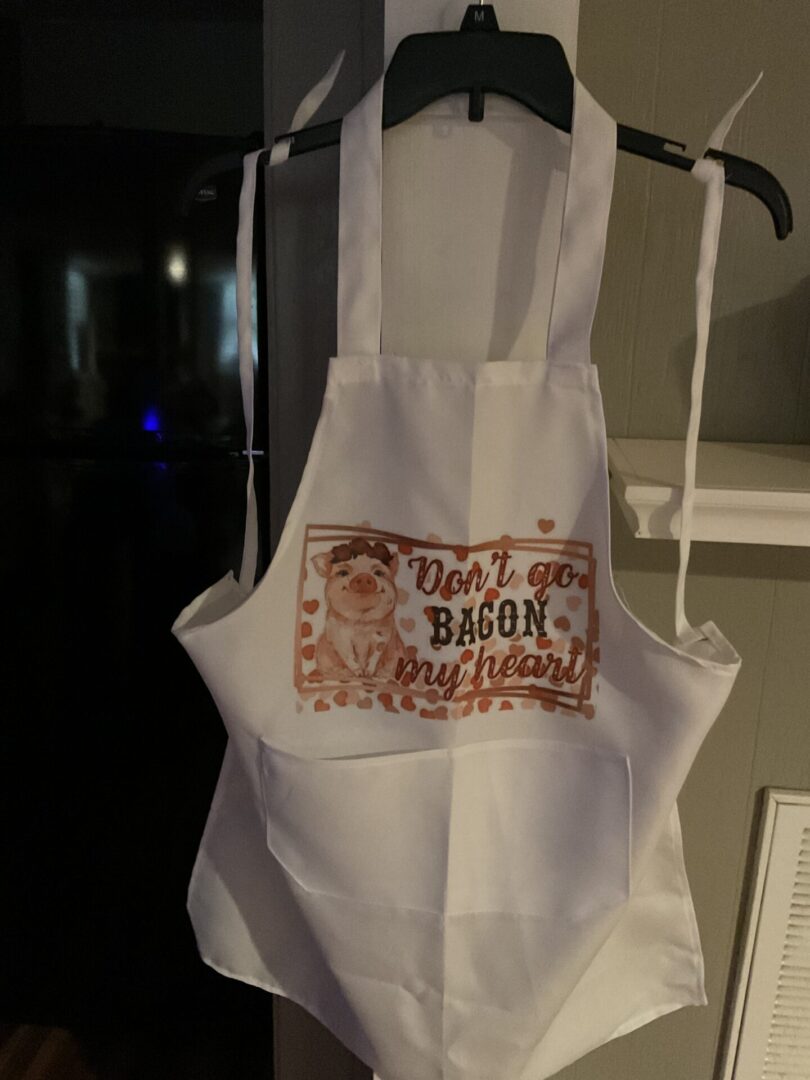 A white apron with an image of bacon on it.