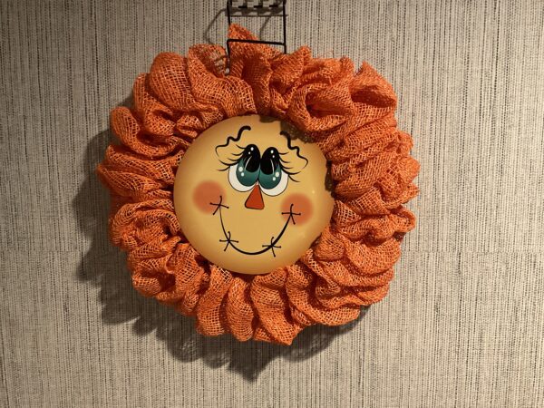 A wreath with an orange face on it.