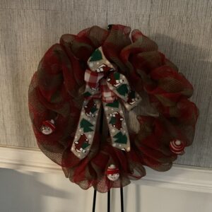 A red and white wreath with a bow on top of it.