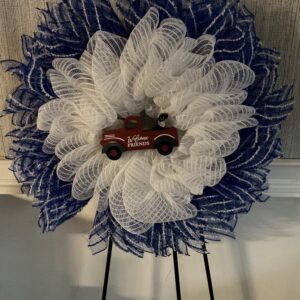 A red truck is sitting on top of a blue and white wreath.