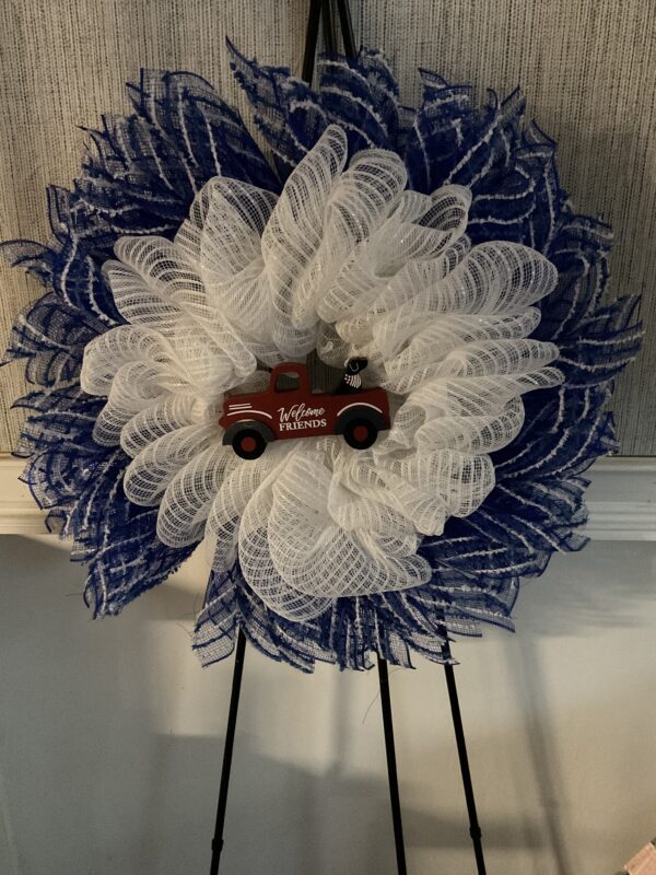 A red truck is sitting on top of a blue and white wreath.