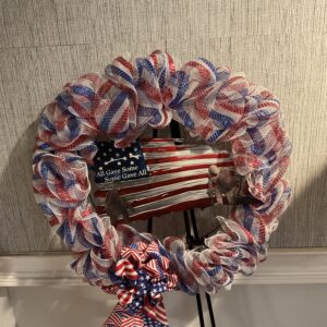 A wreath with red, white and blue ribbons on it.