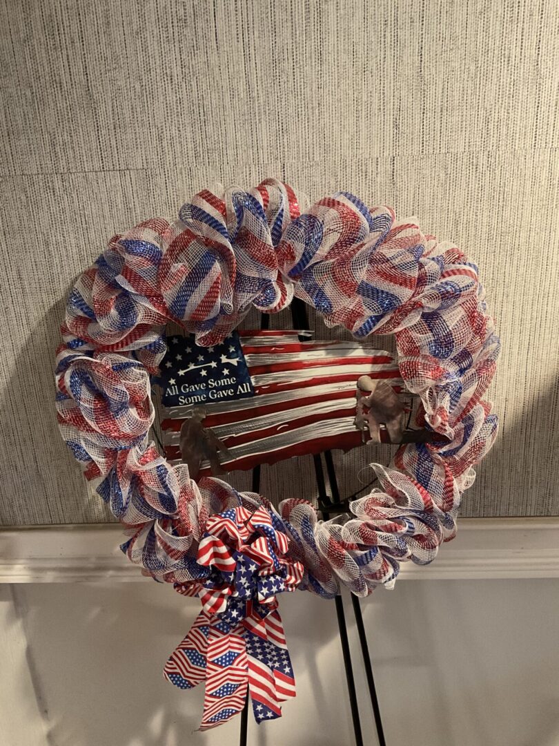 A wreath with red, white and blue ribbons on it.