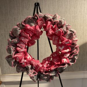 A wreath on a stand with pink and white fabric.