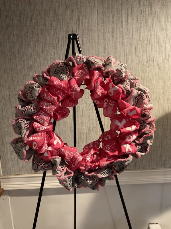 A wreath on a stand with pink and white fabric.