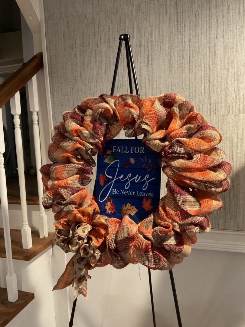 A wreath with a sign hanging on the side of it.