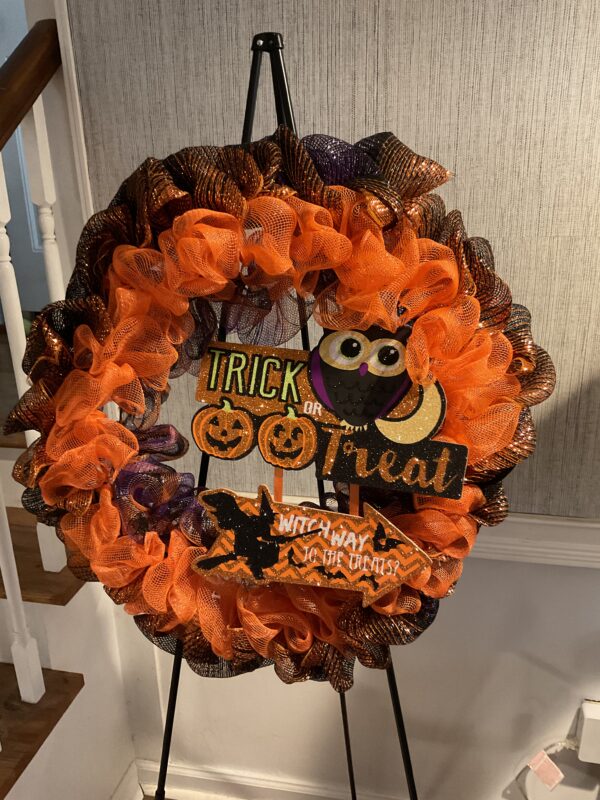 A wreath with orange and black ribbons on it.