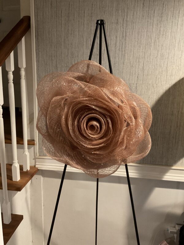 A large flower sitting on top of an easel.