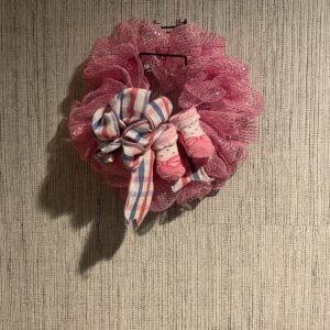 A pink wreath with plaid bow hanging on the wall.