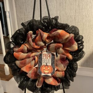 A wreath with black mesh and orange ribbon.