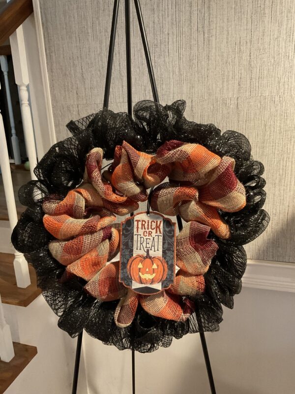 A wreath with black mesh and orange ribbon.